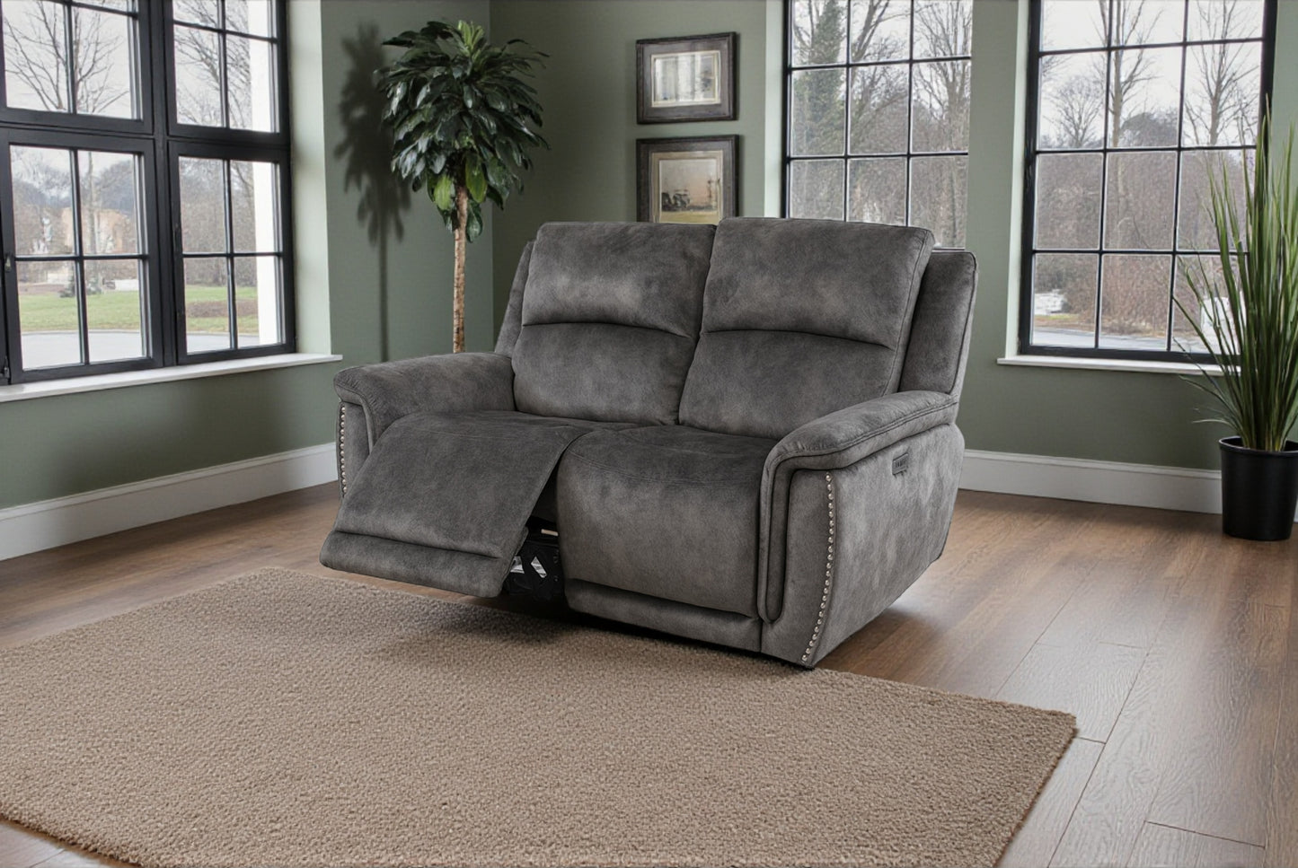Gray recliner chair in a room with large windows and plants.