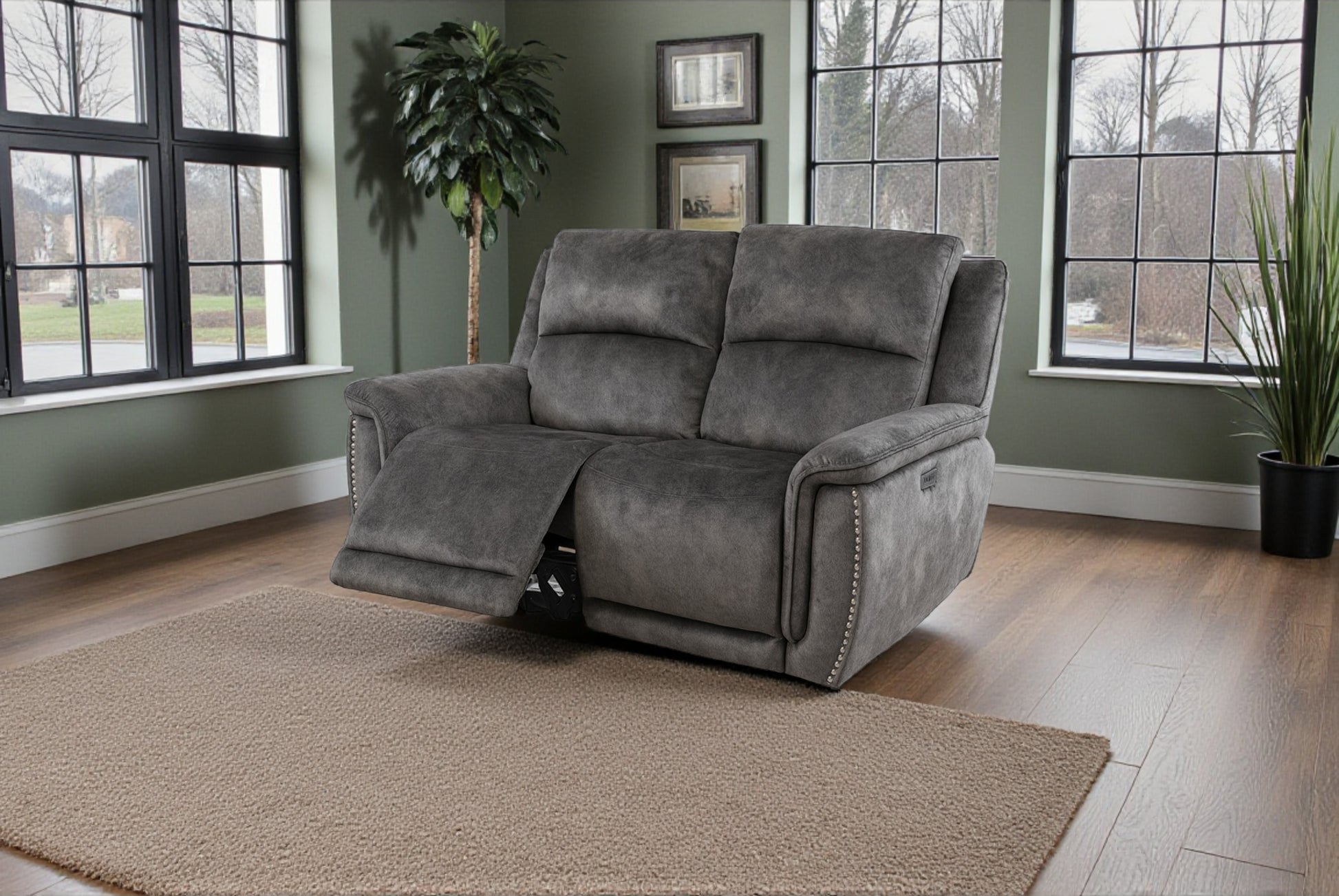 Gray recliner chair in a room with large windows and plants.