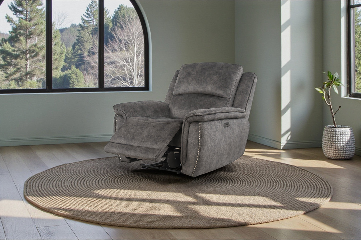 Gray recliner chair in a room with large windows and a plant.