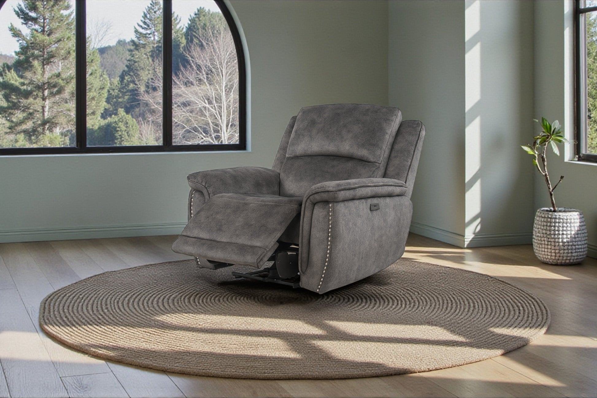 Gray recliner chair in a room with large windows and a plant.