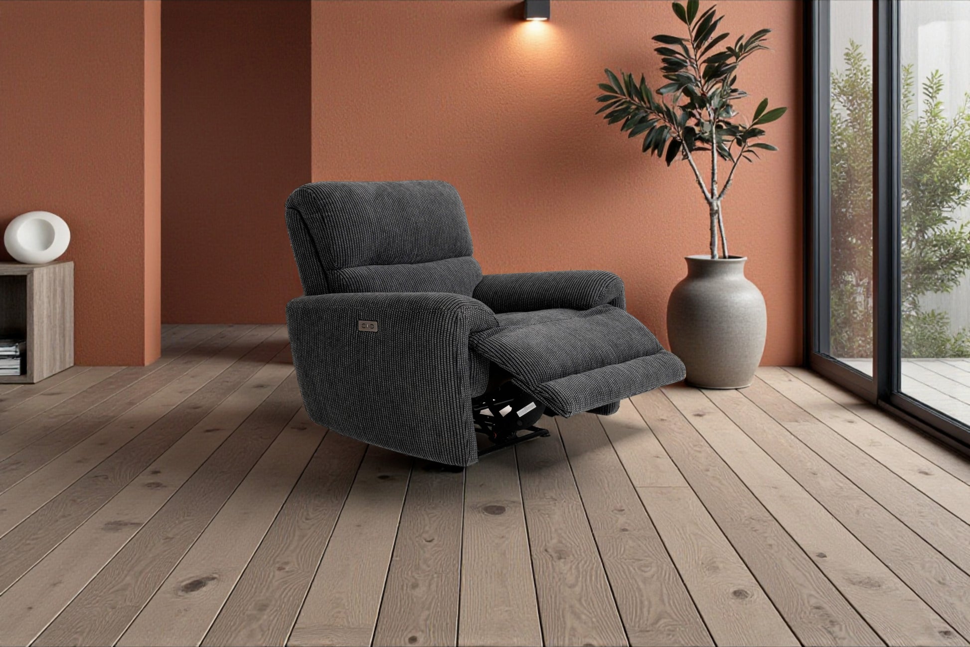 Gray recliner chair in a room with wooden flooring and a large window.