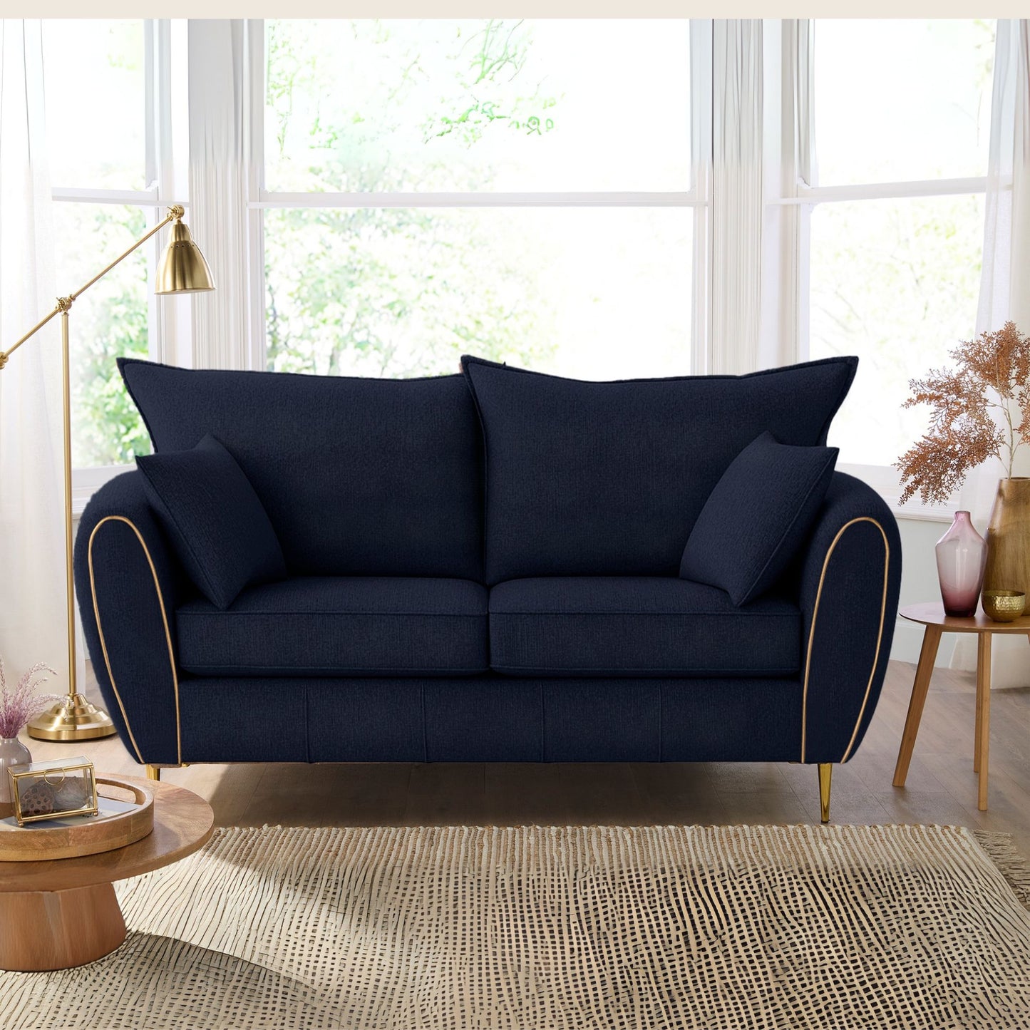 Navy blue sofa in a living room with large windows and decorative elements.