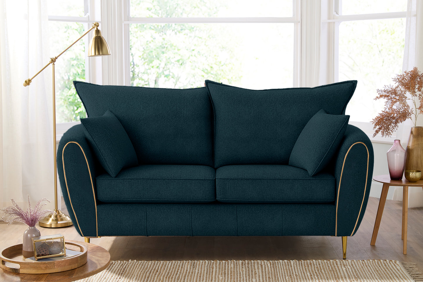 Teal sofa with decorative pillows in a bright living room setting