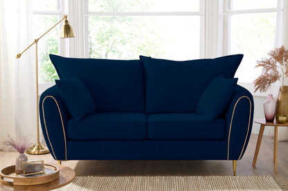 Navy blue sofa with gold trim in a bright room with large windows.