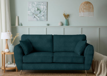 Teal sofa in a living room with decorative elements and a light green wall.