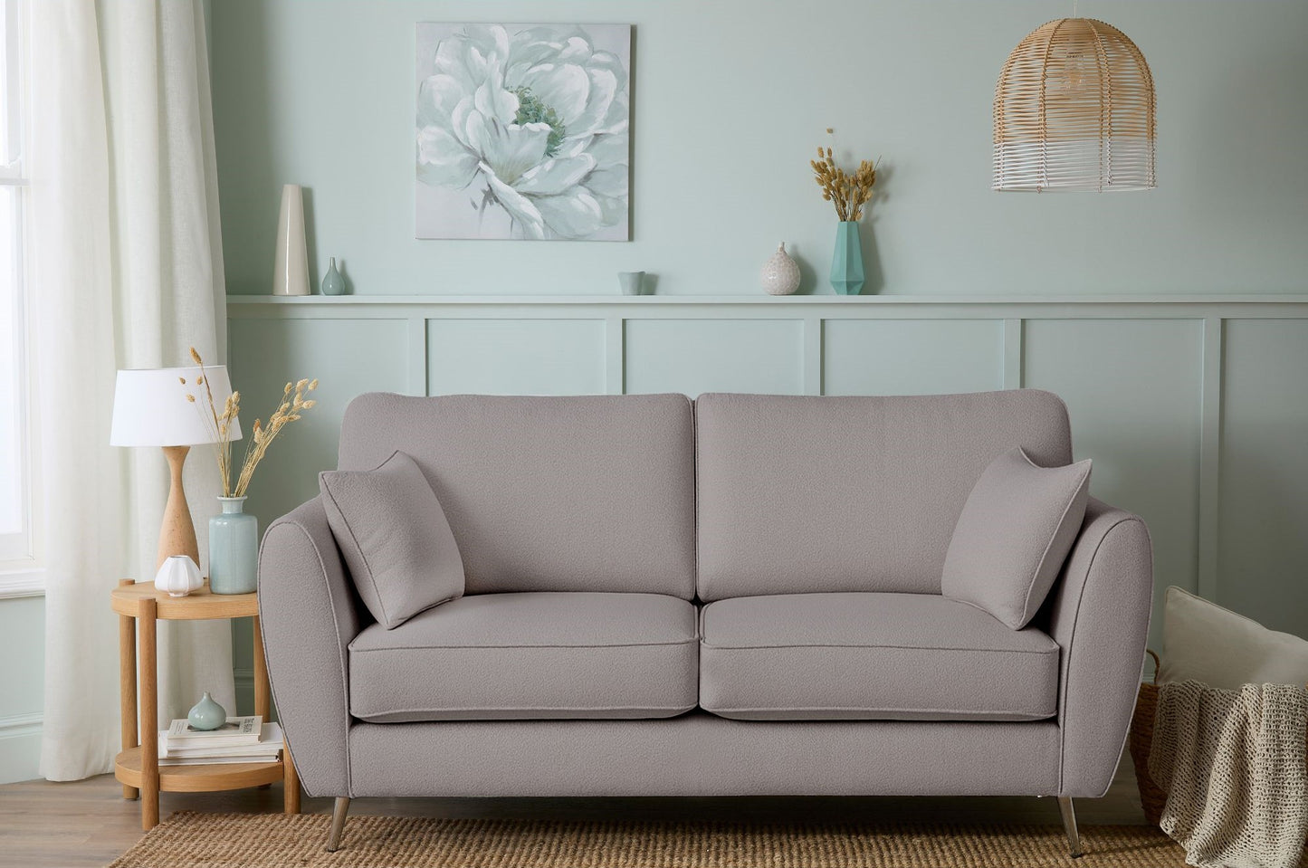 Gray sofa in a living room with decorative items on a shelf and a lamp.