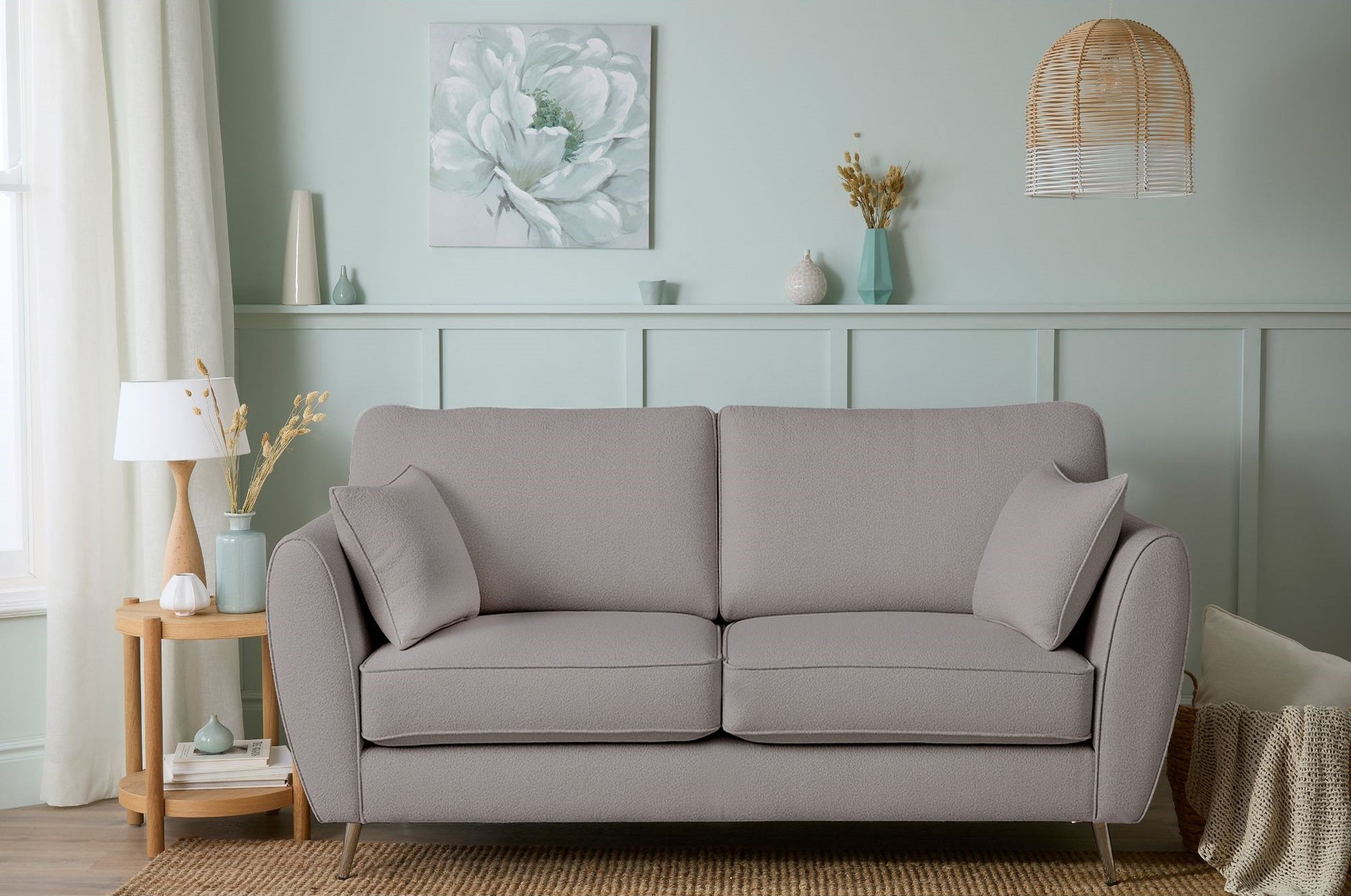 Gray sofa in a living room with decorative items on a shelf and a lamp.