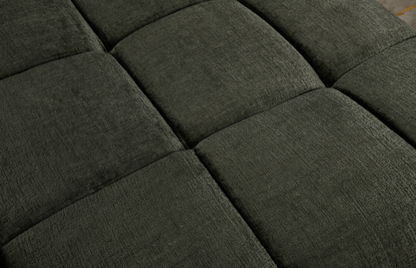 Close-up of a dark green upholstered headboard with tufted design
